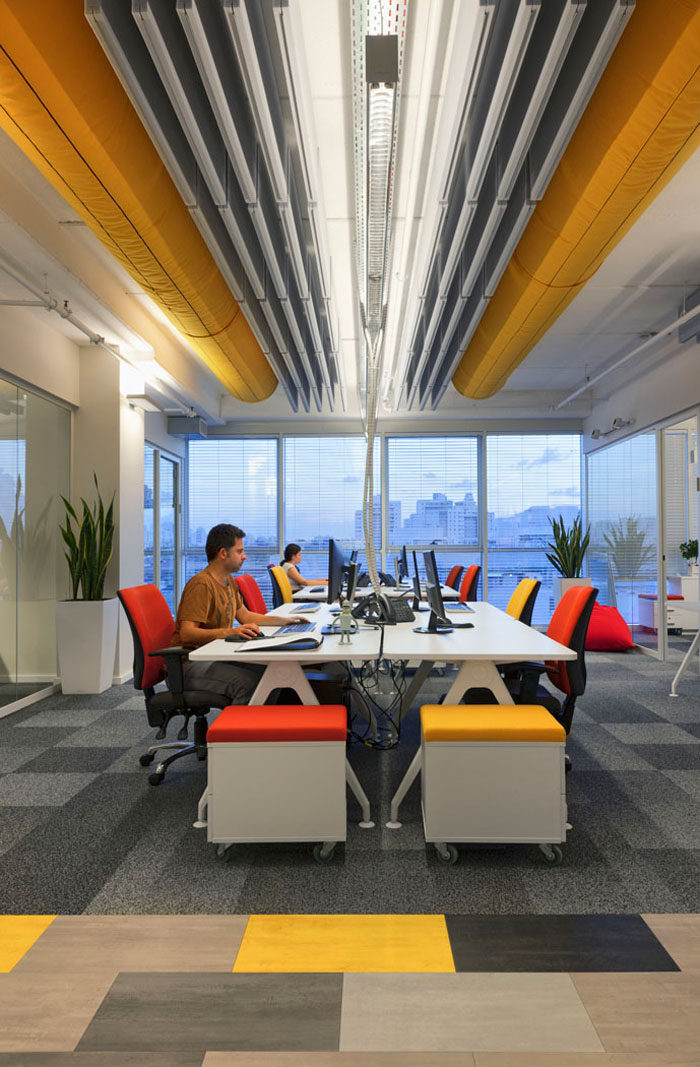עיצוב אופן ספייס צבעוני עם תקרה חשופה במשרדי חברת הייטק. עיצוב משרדים צבעוני בגווני כתום, צהוב אדום ואפור.